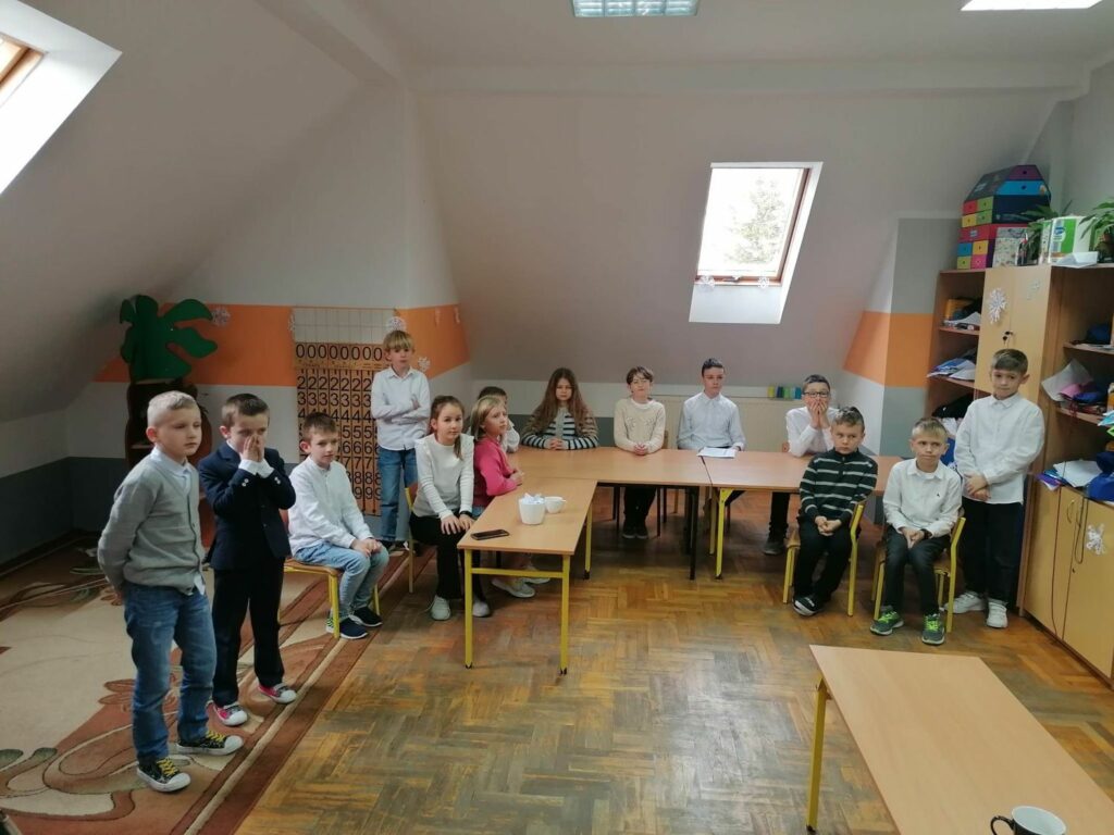 W szkolnej sali zgromadzili się uczniowie biorący udział w szkolnym konkursie „Pięknego Czytania” i słuchają pani nauczycielki, która tłumaczy im zasady rywalizacji.