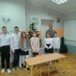 Jedna z grup dzieci biorących udział w konkursie razem z panem bibliotekarzem ustawiła się obok pięknie udekorowanej choinki do pamiątkowego zdjęcia.