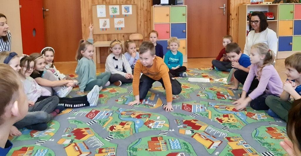 na zdjęciu widać sale przedszkolną dzieci siedzące na podłodze.