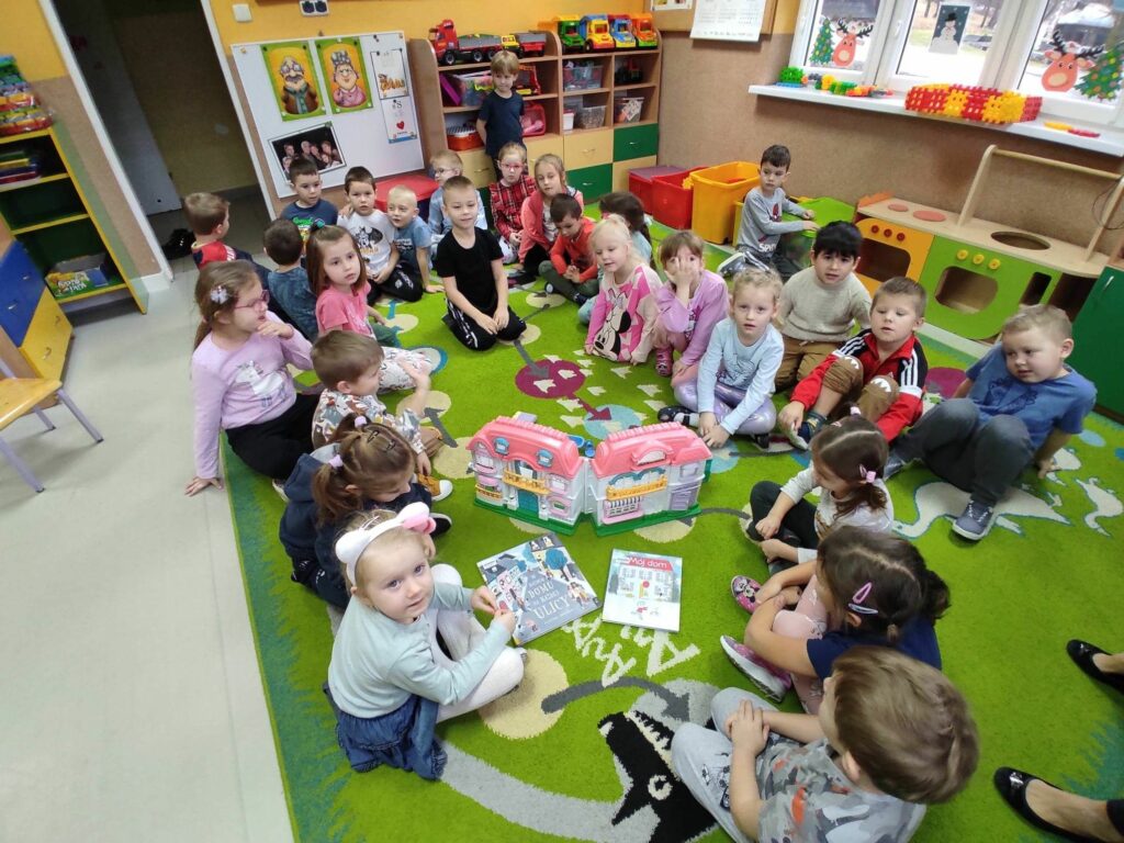 na zdjęciu widać sale przedszkolną, na dywanie siedzą dzieci