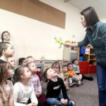 na zdjęciu widać bibliotekarkę pokazującą dzieciom dinozaura
