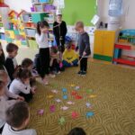 Na zdjęciu widać salę przedszkolną a w niej na dywanie grupa dzieci bawi sie w łowienie rybek