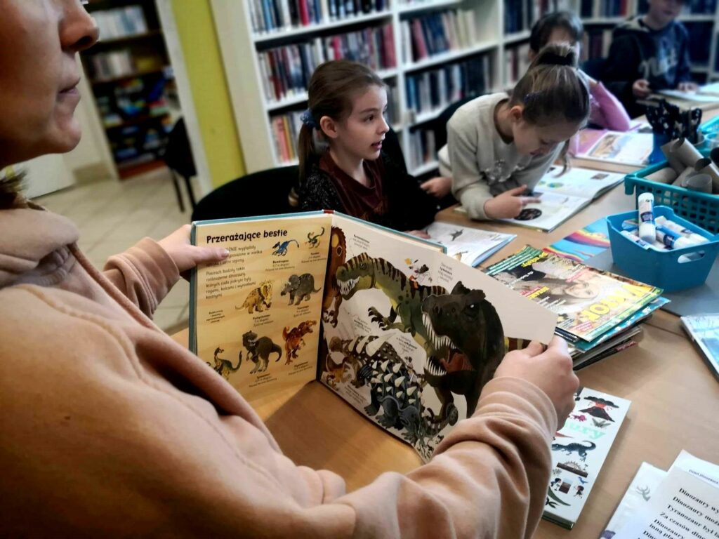 na zdjęciu widać książki o dinozaurach i dzieci