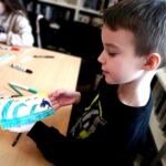 na zdjęciu widać chłopca trzymającego kolorową prace - patyczkowe puzzle
