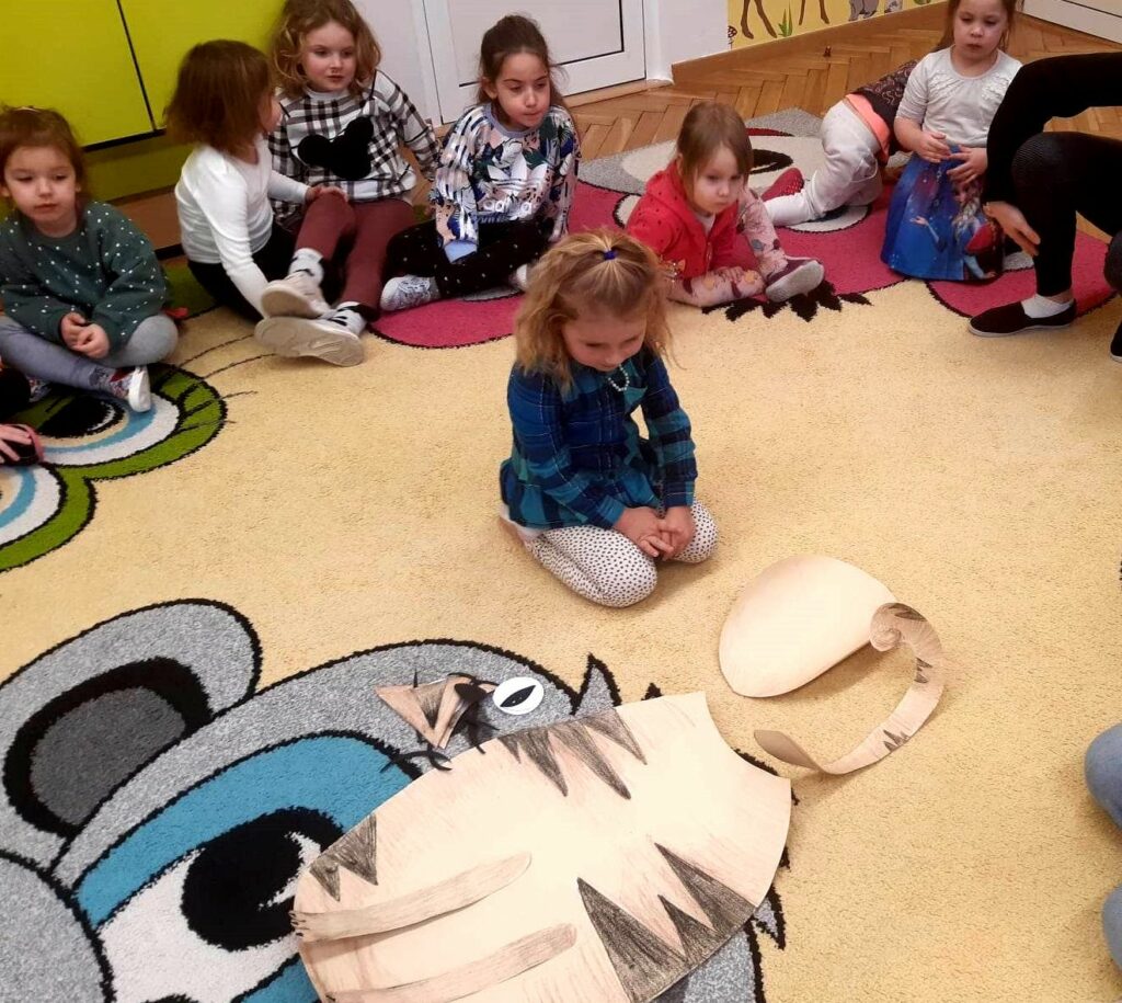 na zdjęciu widać kolorowy dywan i siedzące na nim dzieci