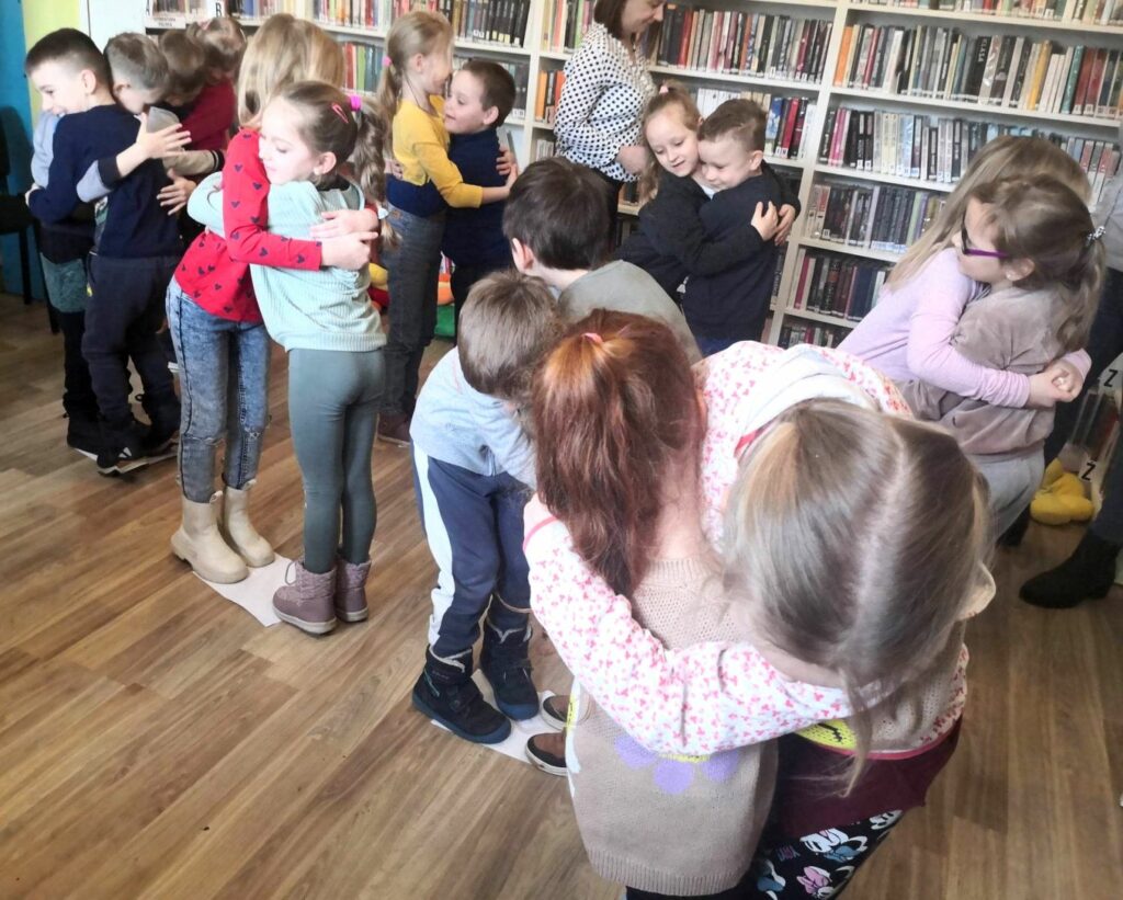 na zdjęciu widać przytulające się dzieci stojące w bibliotece