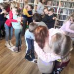 na zdjęciu widać przytulające się dzieci stojące w bibliotece