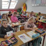na zdjęciu widać salę szkolną, dzieci siedzą przy stolikach, rysują ilustracje
