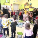 na zdjęciu widać dzieci siedzące na kolorowym dywanie. wraz z dziećmi siedzi również siostra zakonna
