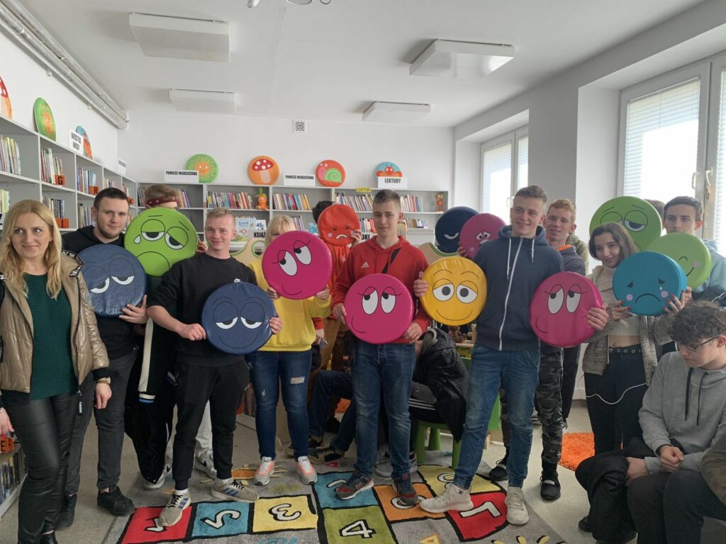 Na zdjęciu grupa młodzieży stoi z poduszkami z emotikonami