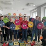 Na zdjęciu grupa młodzieży stoi z poduszkami z emotikonami