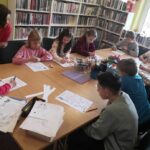 na zdjęciu widać dzieci siedzące wokół stołu w sali bibliotecznej