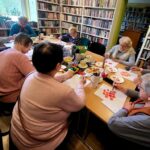 na zdjęciu stół i siedzące przy nim malujące seniorki