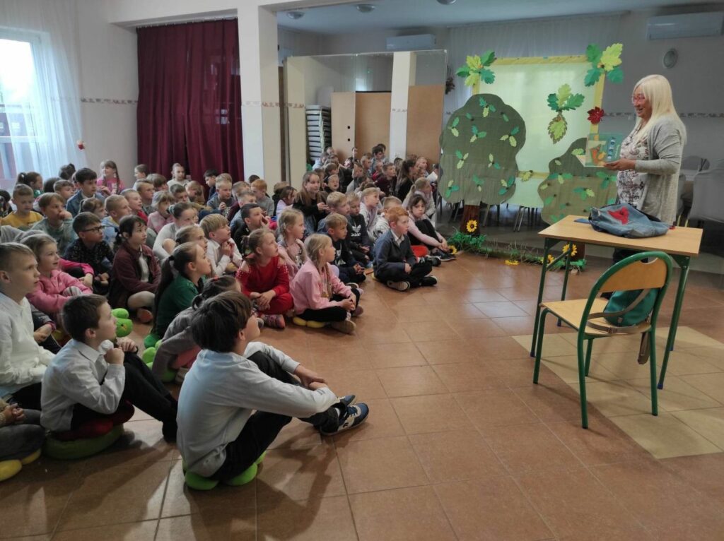 na zdjęciu widać dzieci, siedzą na podłodze, autorka prezentuje swoją książkę