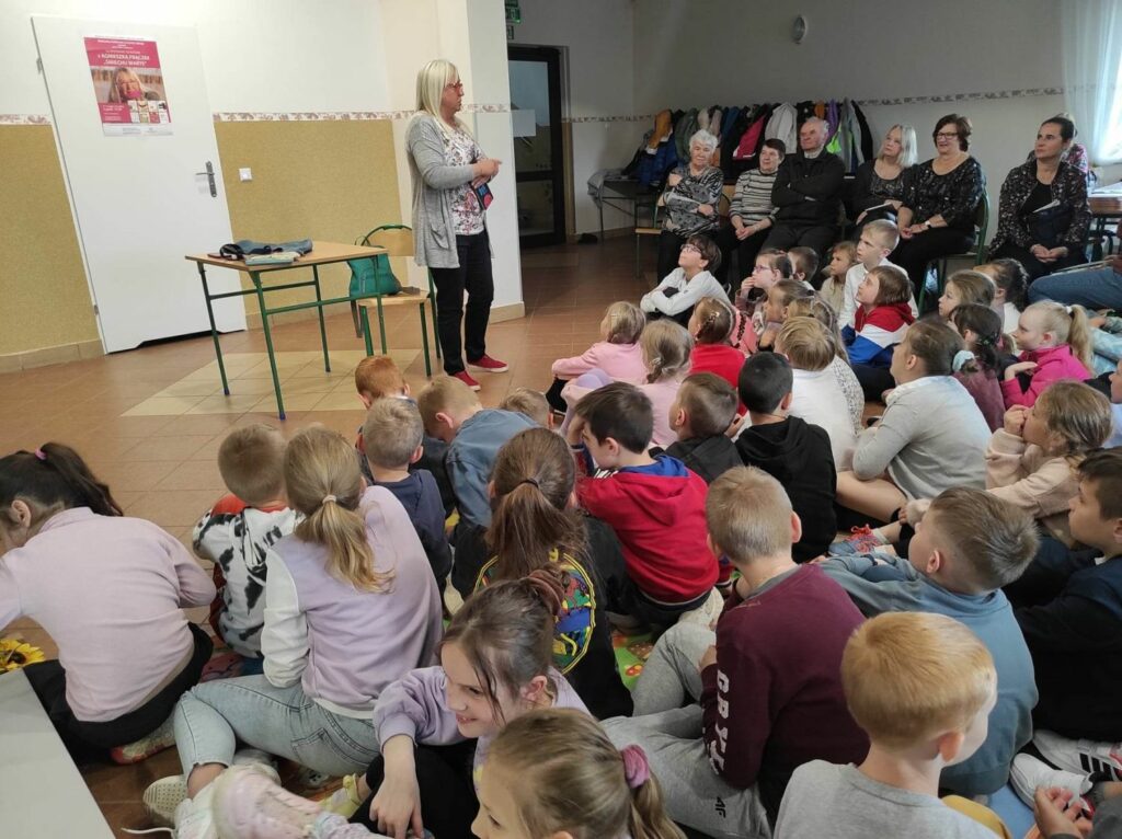 na zdjęciu widać dzieci i seniorów, autorka prezentuje swoją książkę