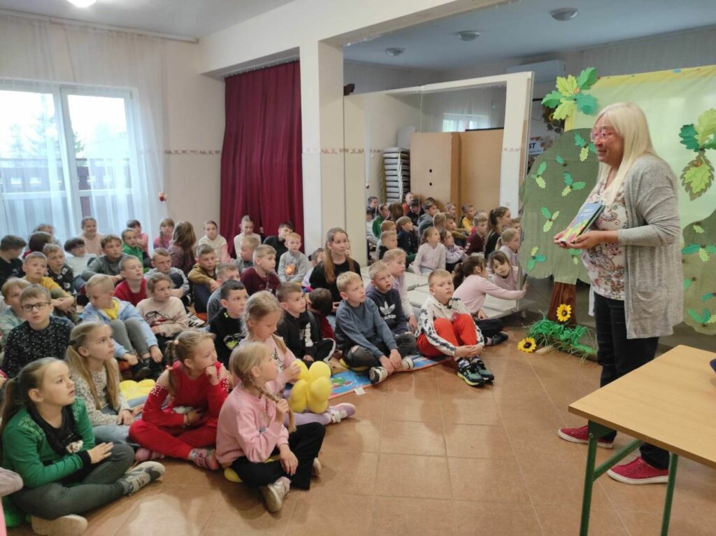 na zdjęciu widać dzieci, siedzą na podłodze, autorka prezentuje swoją książkę