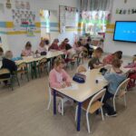 na zdjęciu widać salę przedszkolną, dzieci siedzą przy stolikach, wykonują pracę plastyczną