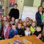 Na zdjęciu widać salę biblioteczną, na zdjęciu widać dzieci odwiedzające bibliotekę, wychowawcę przedszkolnego i bibliotekarza