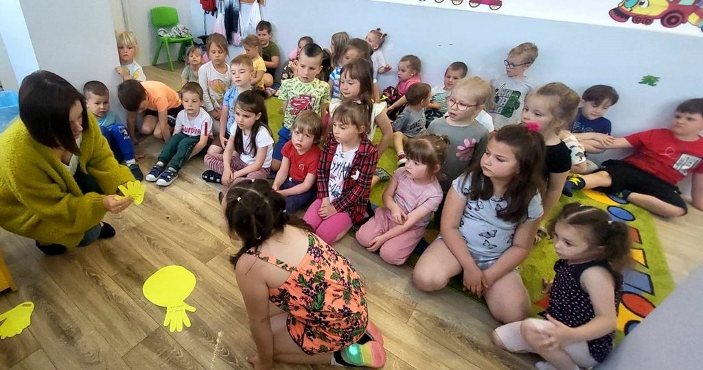 na zdjęciu widać dzieci siedzące na podłodze