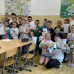 na zdjęciu widać bibliotekarza wraz z uczniami przedstawiającymi swoje prace plastyczne
