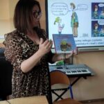 na zdjęciu widać kobietę bibliotekarkę stojąca z książką w ręku