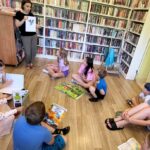 na zdjęciu widać bibliotekarkę pokazującą dzieciom ilustracje przedstawiająca ślimaka