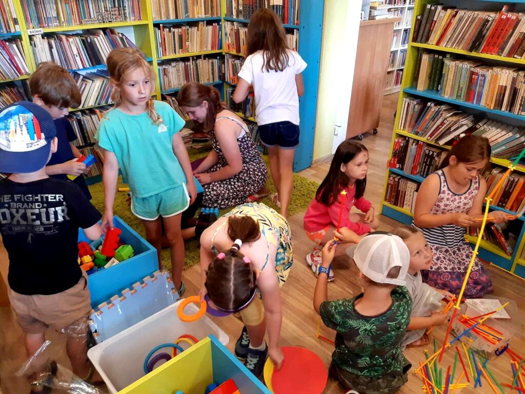 na zdjęciu widać dzieci w sali bibliotecznej układające klocki