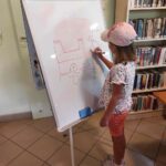 na zdjęciu widać dziecko, stoi przy tablicy, rysuje hasło podczas gry w kalambury