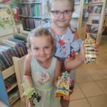 na zdjęciu widać salę biblioteczną, dzieci prezentują prace plastyczne