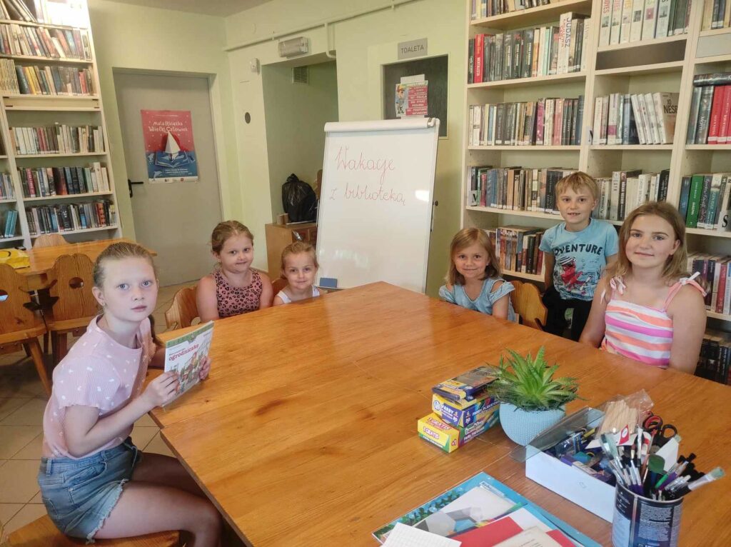 na zdjęciu widać salę biblioteczną, przy stole siedzą dzieci
