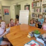 na zdjęciu widać salę biblioteczną, przy stole siedzą dzieci