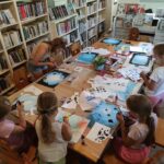 na zdjęciu widać salę biblioteczną, przy stole siedzą dzieci