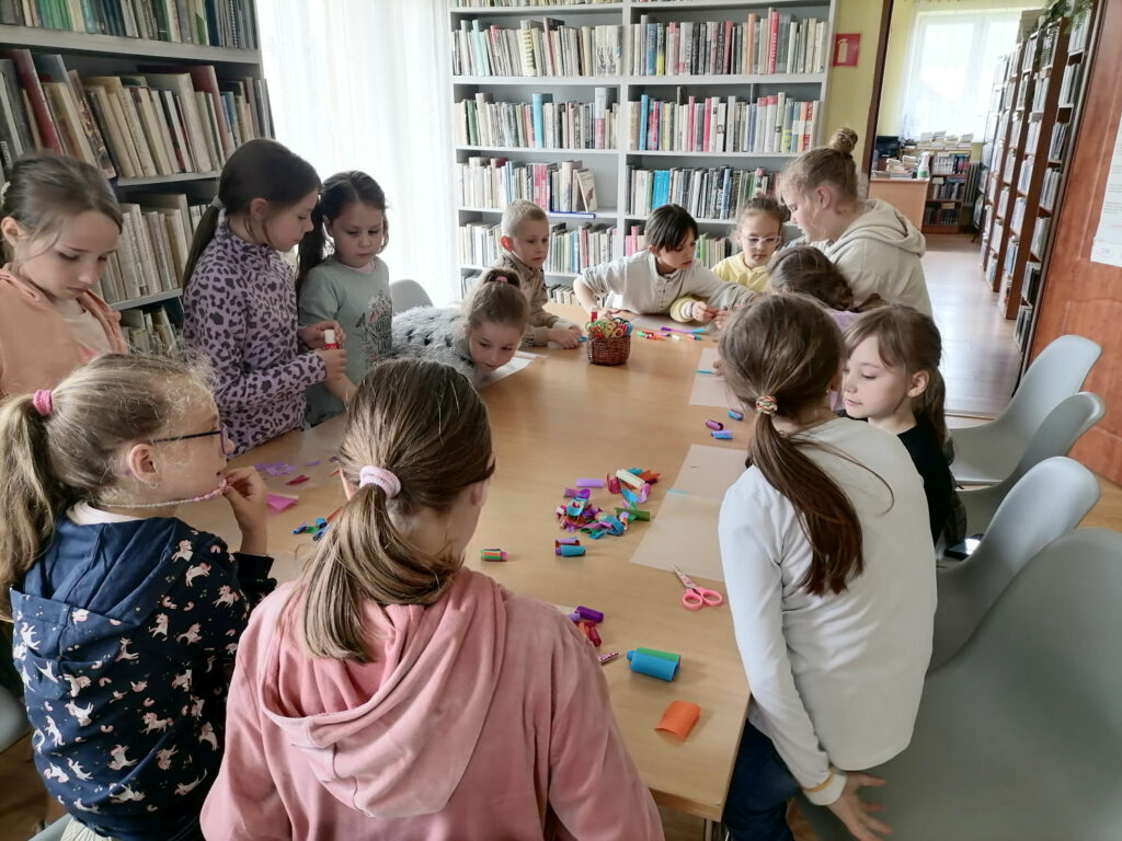 Na zdjęciu widoczna jest grupa dzieci podczas wykonywania elementów dekoracyjnych latawca.