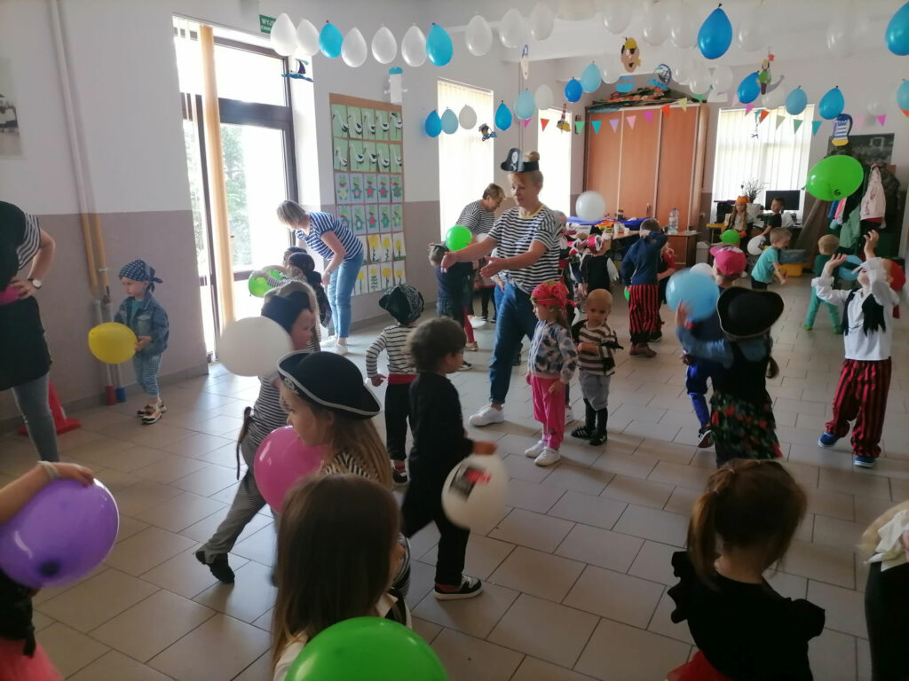 na zdjęciu widoczne są przedszkolaki oraz ich wywchowawcy podczas zabawy z balonami.