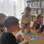 Na zdjęciu widoczna jest grupa 4 przedszkolaków podczas zabawy schematycznej z kolorowymi, plastikowymi jajkami.