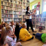 na zdjęciu widać bibliotekarkę pokazującą dzieciom książkę