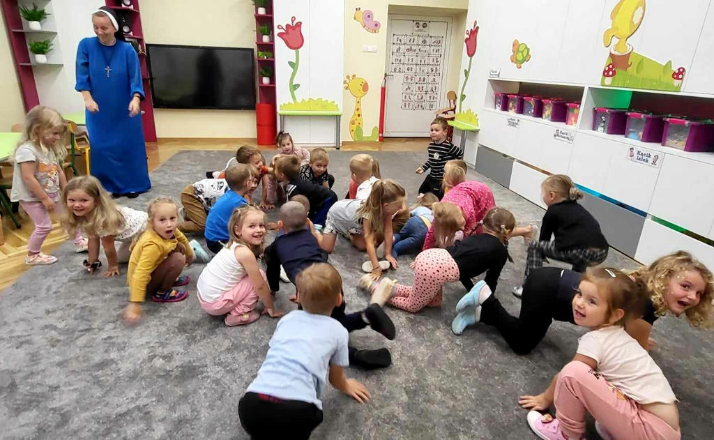 na zdjęciu widać dzieci leżące na popielatej wykładzinie