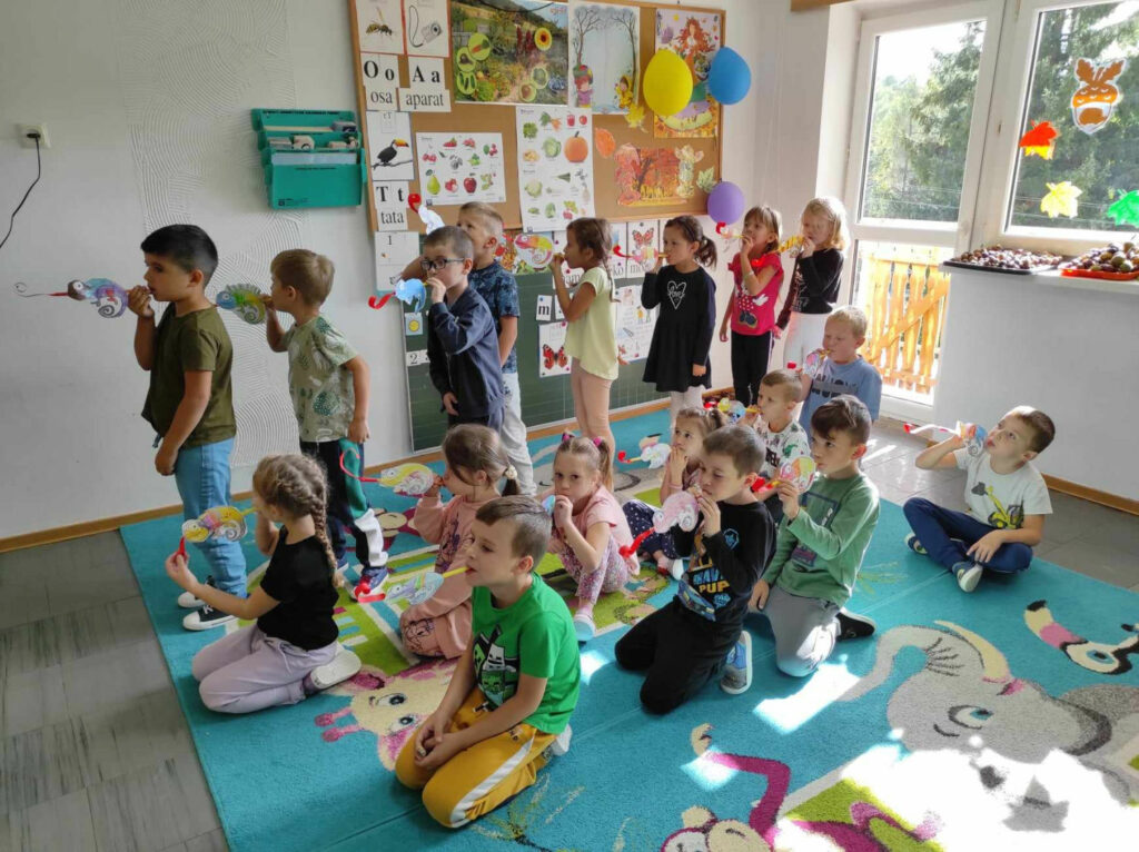 na zdjęciu widać salę przedszkolną, dzieci prezentują wykonane prace plastyczne
