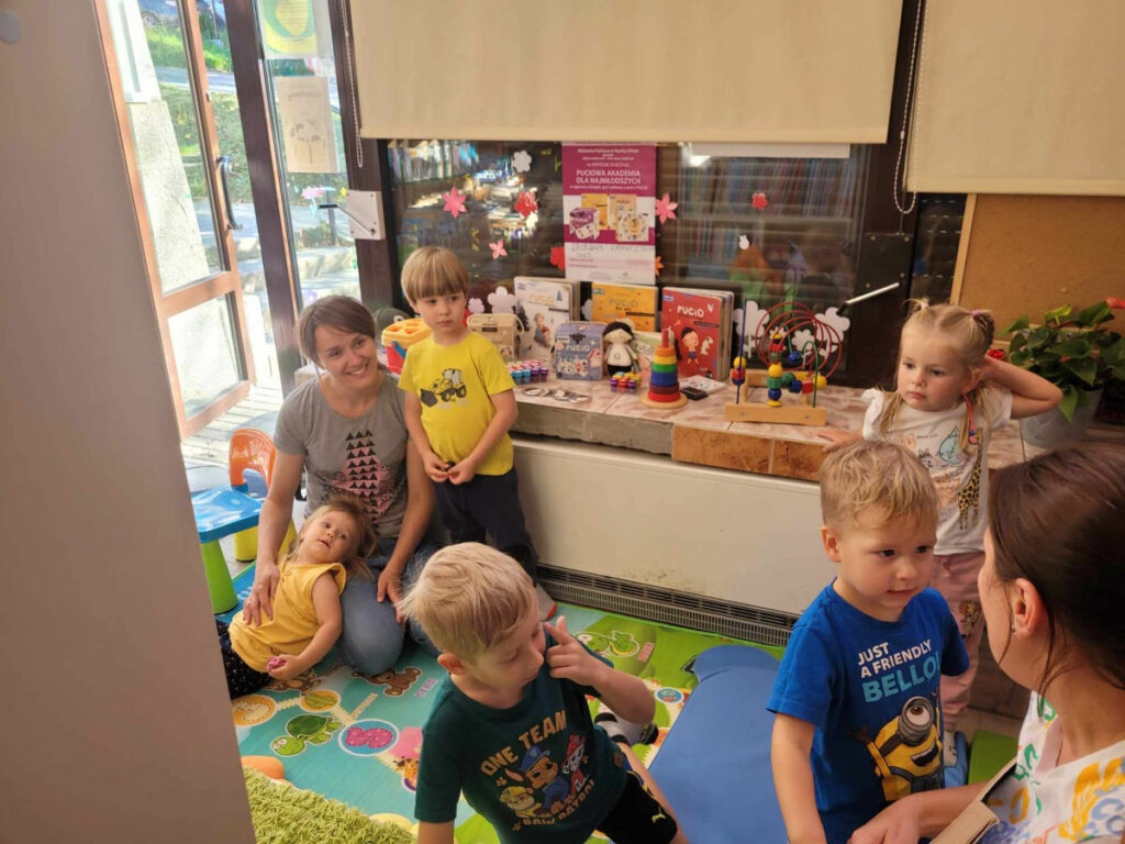 dzieci słuchają bajki czytanej przez bibliotekarza