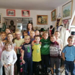 na zdjęciu widoczna jest grupa 13 uczniów (10 dziewczynek i 3 chłopców) pozujących do wspólnego zdjęcia w muzeum. W tle eksponaty muzealne.