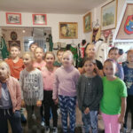 na zdjęciu widoczna jest grupa 13 uczniów (10 dziewczynek i 3 chłopców) pozujących do wspólnego zdjęcia w muzeum. W tle eksponaty muzealne.