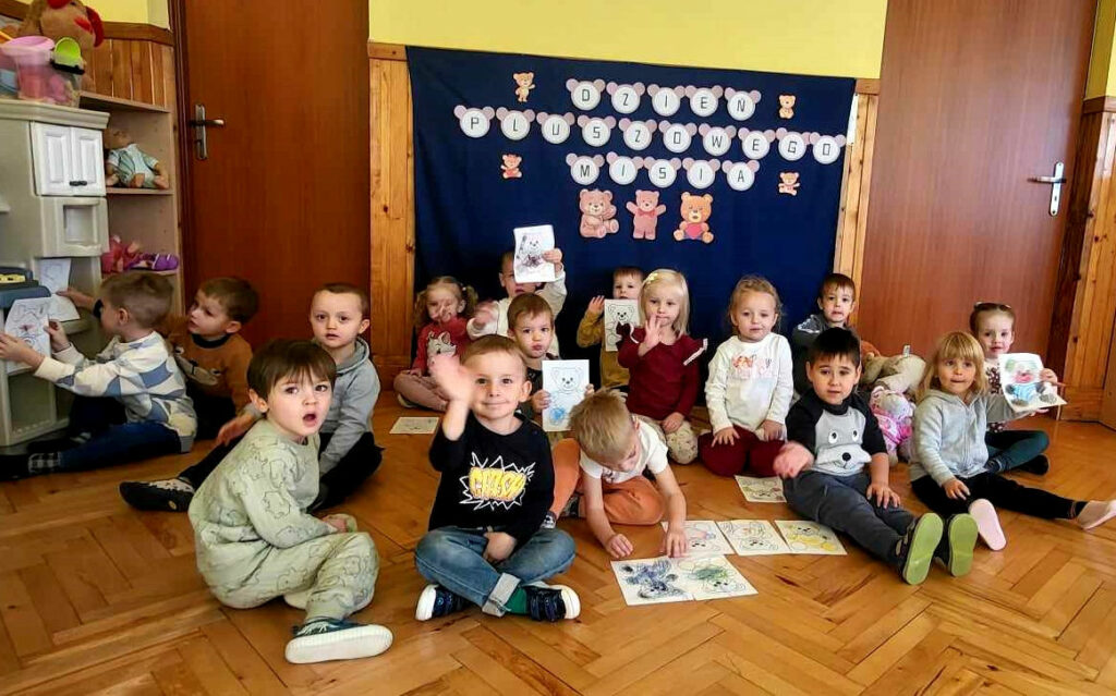 na zdjęciu widać małe dzieci w przedszkolu siedzące na podłodze.