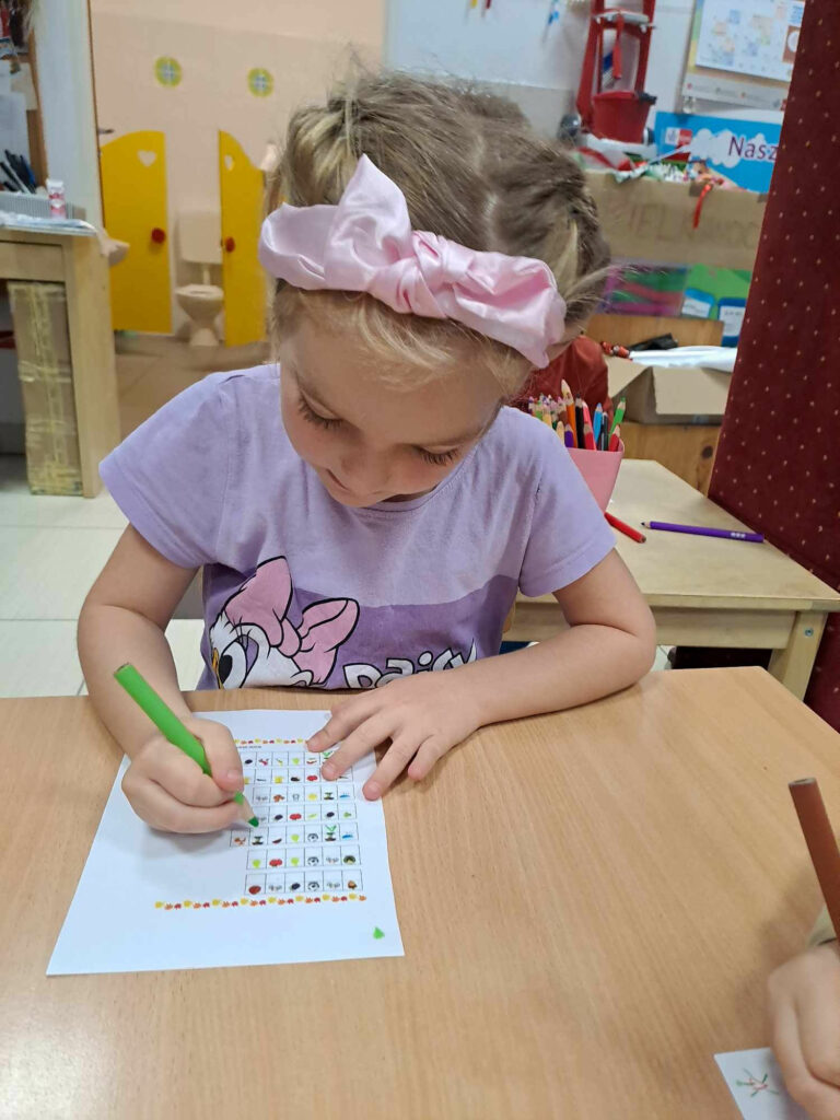 Na zdjęciu dziewczynka siedzi przy stoliku i rysuje