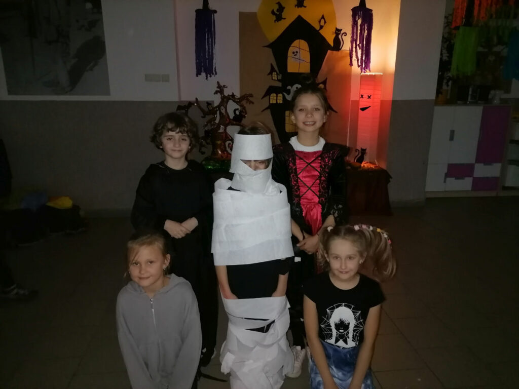 Na zdjęciu widoczne są 4 dziewczynki jedna z nich owinięta papierem toaletowym na podobieństwo mumii.