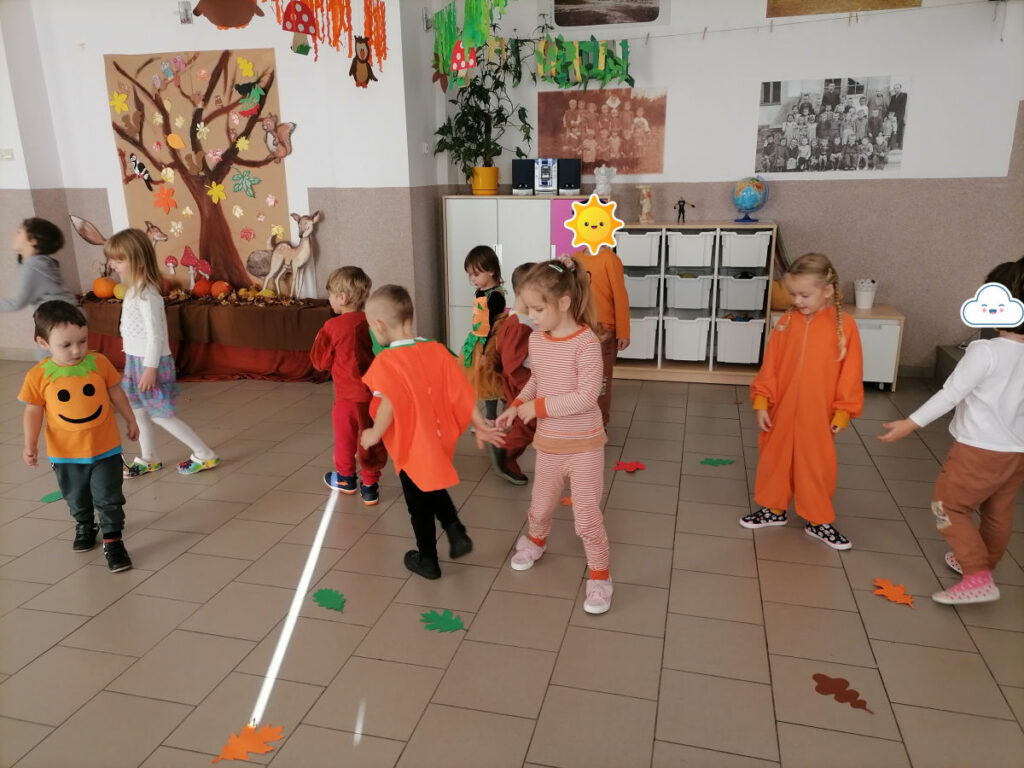 Na zdjęciu widoczna jest grupa przedszkolaków w kolorowych strojach biorących udział w zabawie ruchowej "liście".