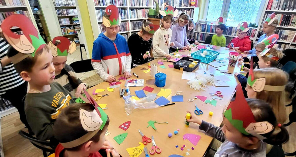 na zdjęciu widać dzieci siedzące wokół stołu w sali bibliotecznej
