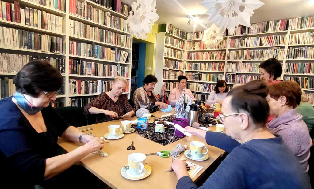 na zdjęciu widać sale biblioteczną i osoby siedzące wokół stołu