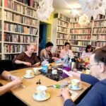 na zdjęciu widać sale biblioteczną i osoby siedzące wokół stołu