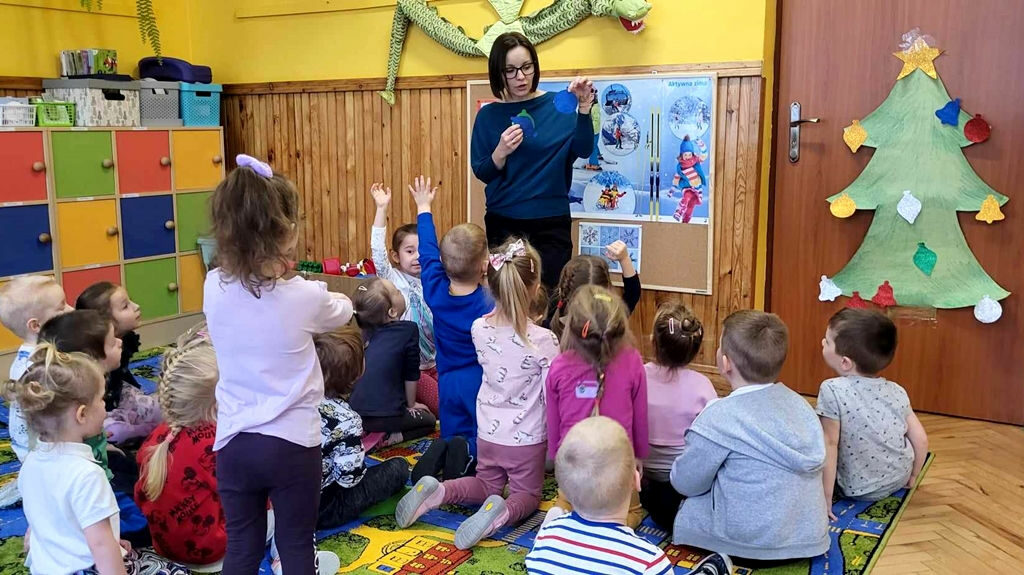 na zdjęciu widać dzieci siedzące przy przedszkolnych