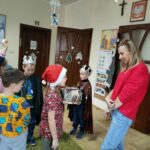 Na zdjęciu widocznych jest 5 przedszkolaków i bibliotekarz podczas składania życzeń świątecznych.